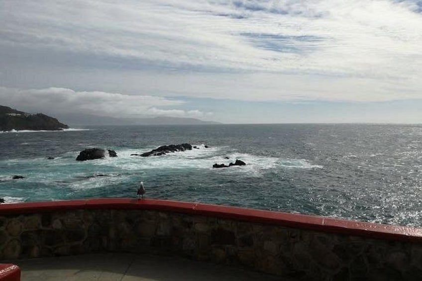 A rocky coastline with waves crashing against the rocks and a clear sky above. 1