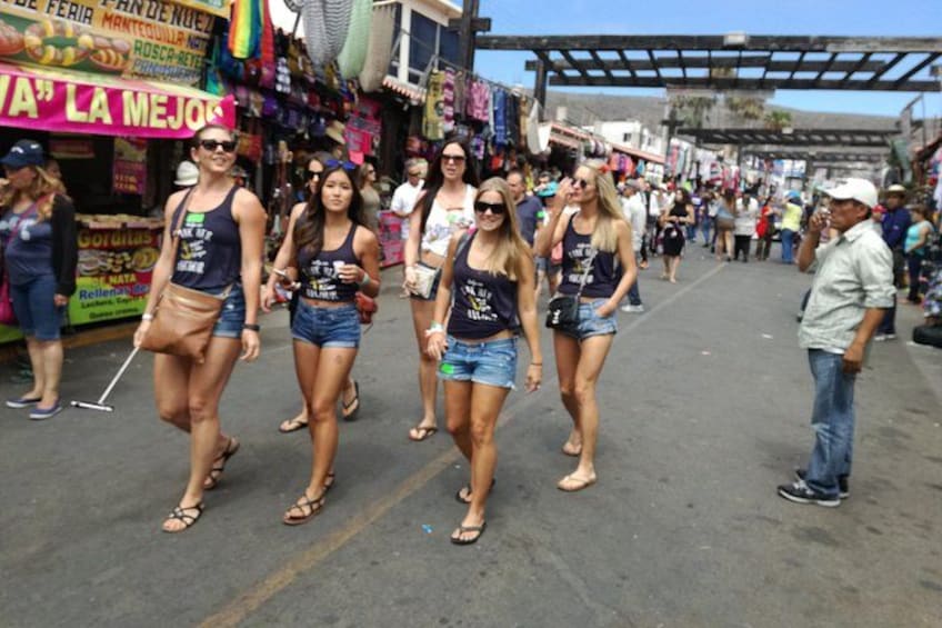 A crowded street with people walking, shops, and a sign that reads 'LA MEJO.' 4