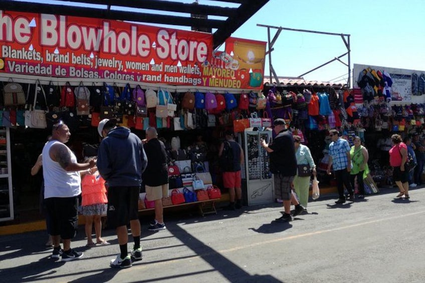 A street market with a store named 'Blowhole Store' selling blankets, belts, jewelry, and handbags. 5
