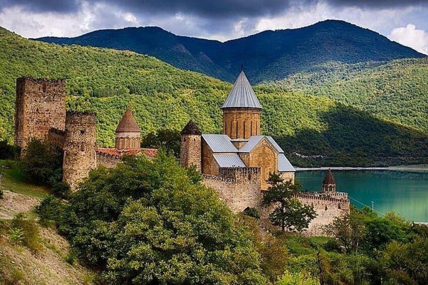 A historic church with a bell tower, surrounded by lush greenery and mountains. 5
