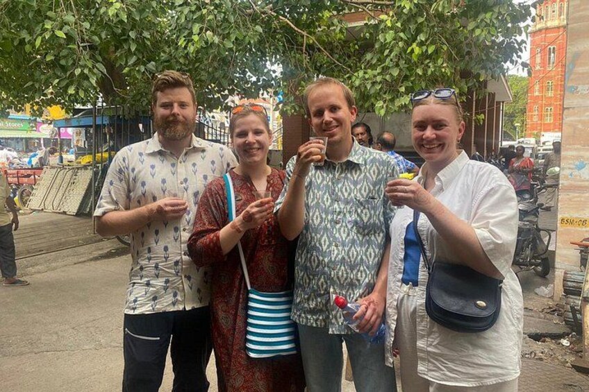 Four people standing outdoors, one holding a drink. 2