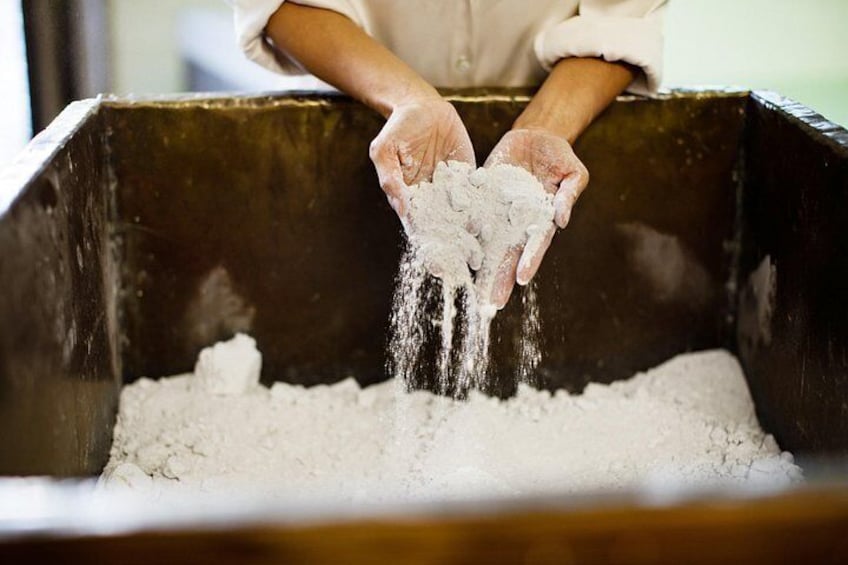 A person pouring flour from a container into a large mixing bowl. 5