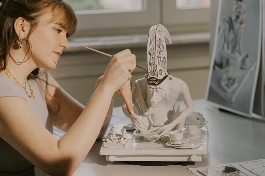 A person painting a sculpture of a seated figure. 3