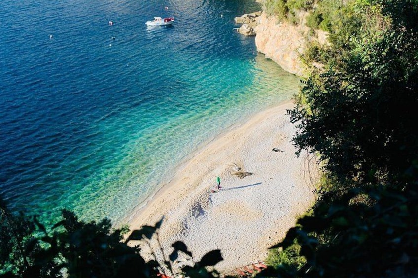 En kyststrand med klart vand, en båd og en person, der går en tur. 2