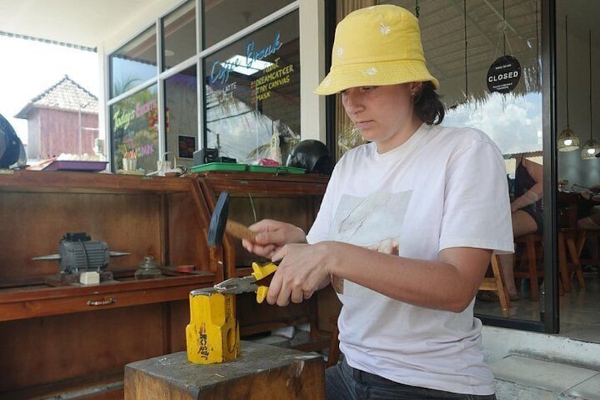 A person using a yellow tool on a wooden workbench. 5