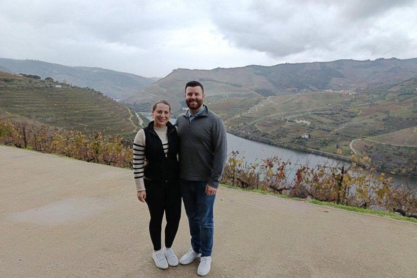 A couple standing on a road with a valley and lake in the background. 4