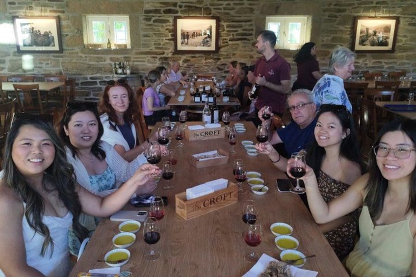 A group of people seated at a long wooden table in a restaurant with a stone wall background. 5