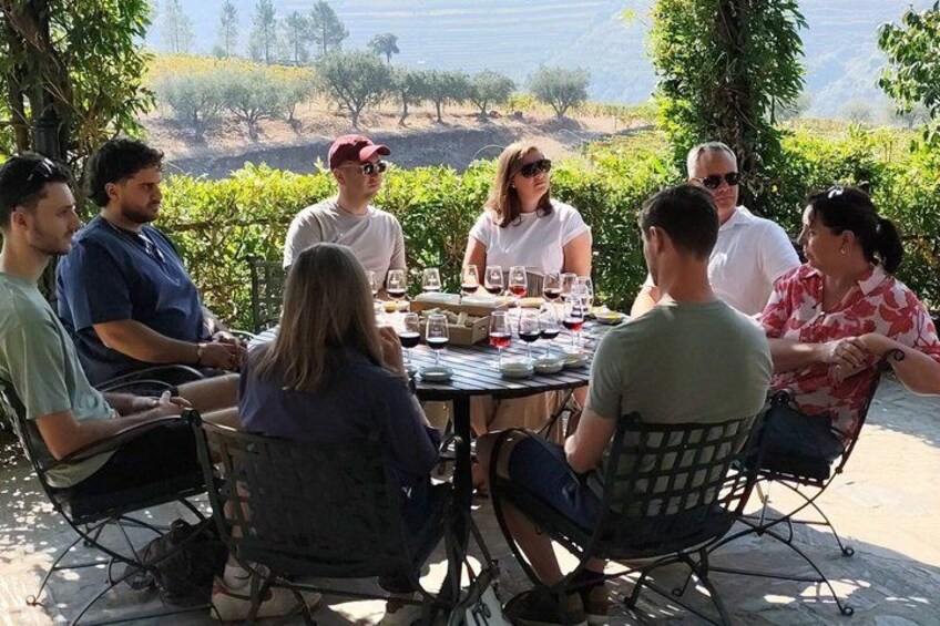 A group of people sitting around a table outdoors with a scenic view in the background. 2