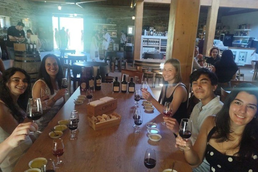 Un gruppo di persone sedute attorno a un tavolo di legno, con bicchieri da vino e bottiglie. 4