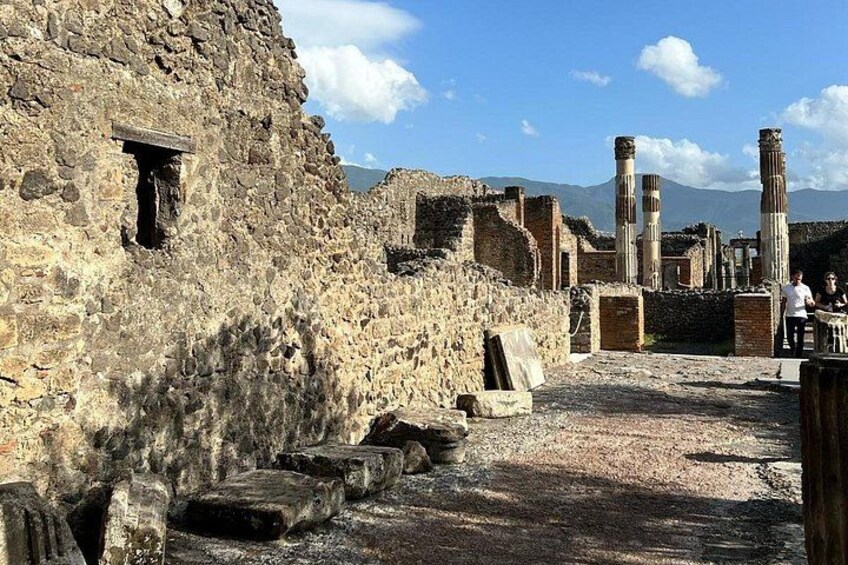 Ancient ruins with stone walls and columns, a clear sky, and mountains in the background. 4
