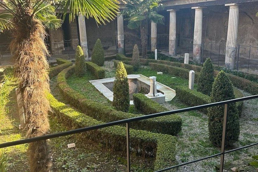 A landscaped garden with a fountain, palm trees, and classical columns. 2
