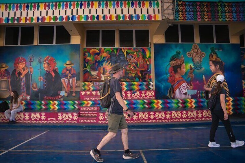 A person walking on a basketball court with colorful murals on the wall. 3