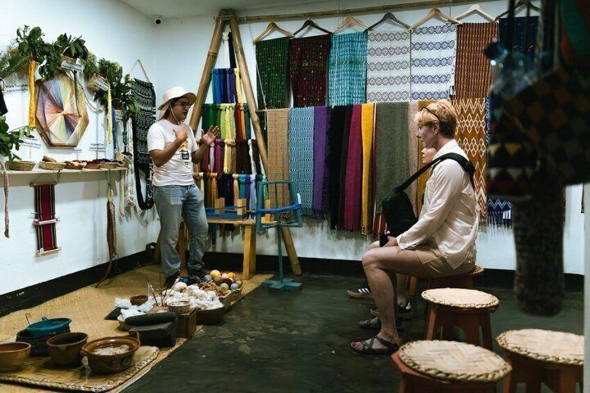 A weaving workshop with colorful textiles, a loom, and various weaving tools. 2