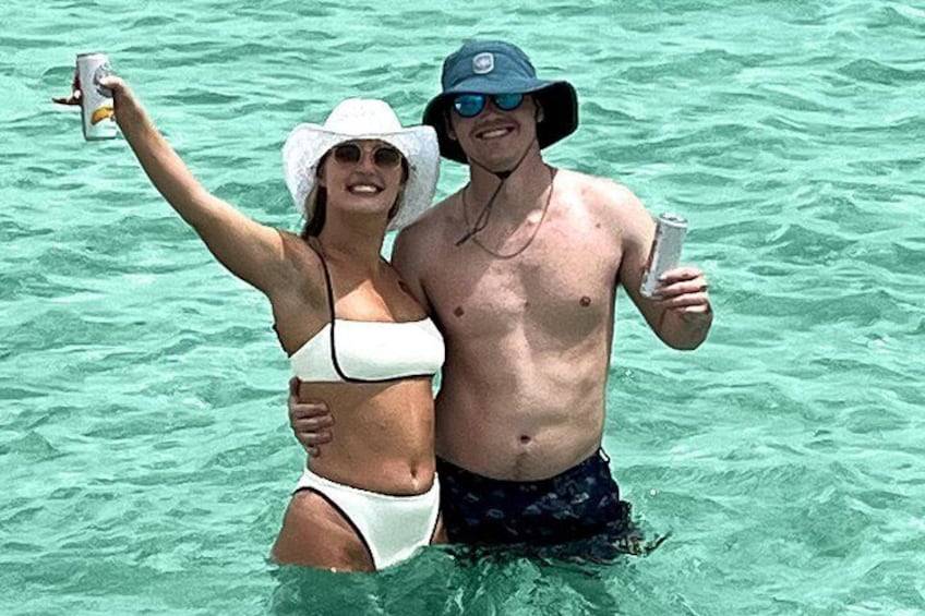 Dos personas en agua cristalina, una sosteniendo una bebida. 3