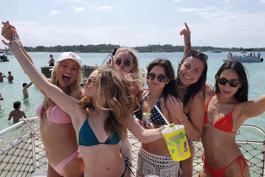 Een groep mensen op een boot, met een meer en andere boten op de achtergrond. 1