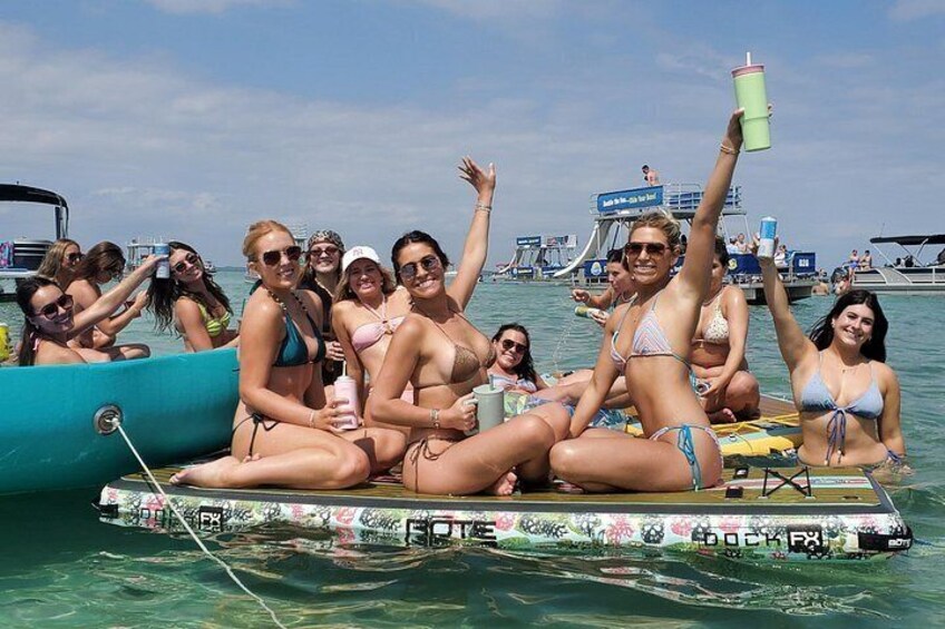 Un grupo de personas en una plataforma flotante en el agua, con barcos al fondo. 2