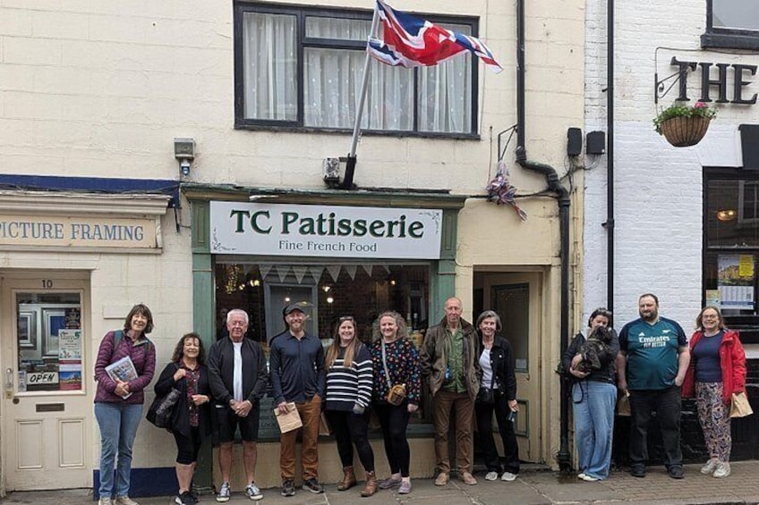 A group of people standing in front of TC Patisserie, a French food restaurant. 4