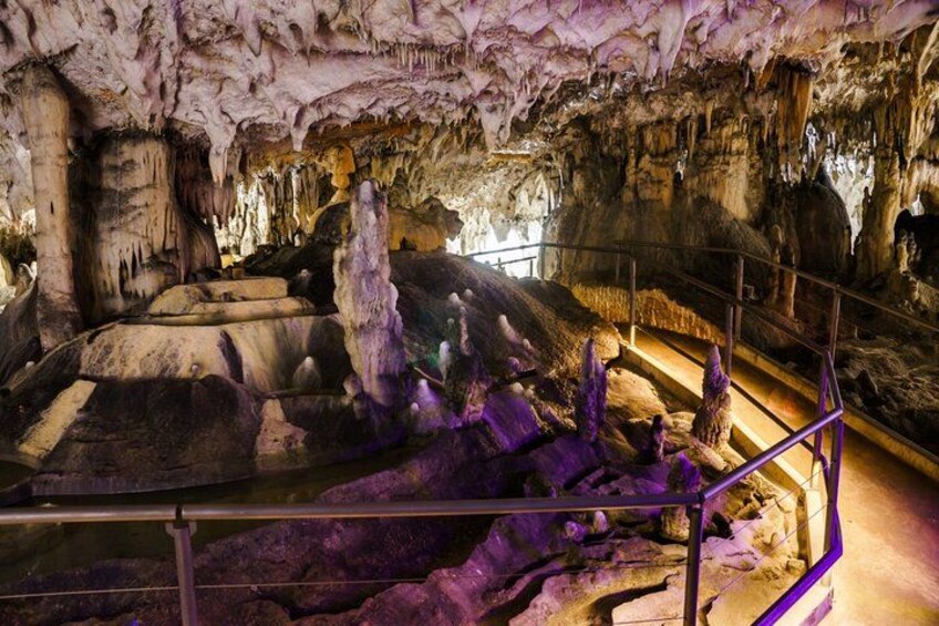 A cave with stalactites and stalagmites, a staircase, and a railing. 2
