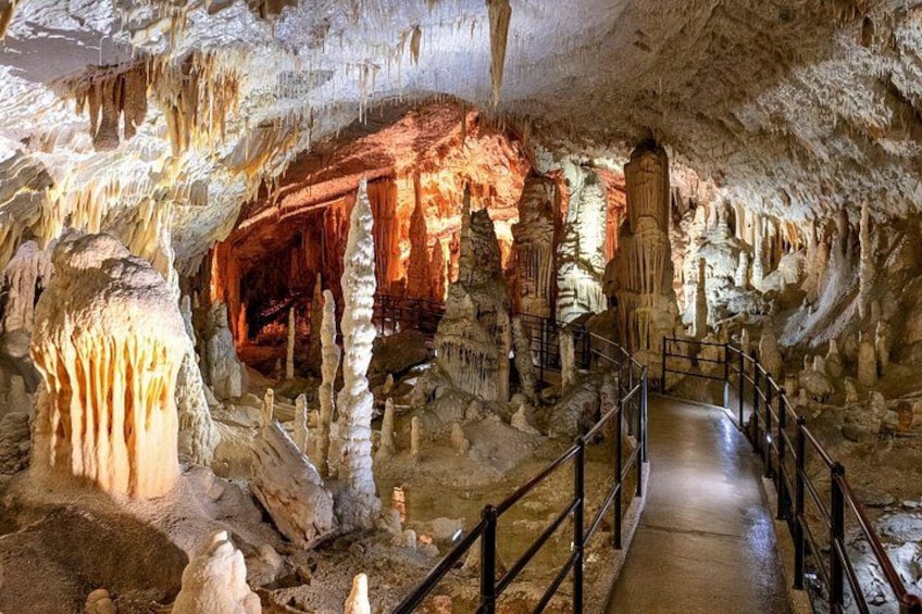 A cave with stalactites and stalagmites, a pathway, and a railing. 2