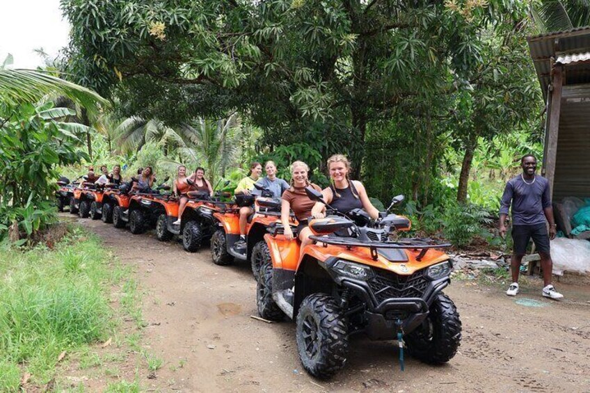 A group of people riding ATVs on a dirt path surrounded by greenery. 1