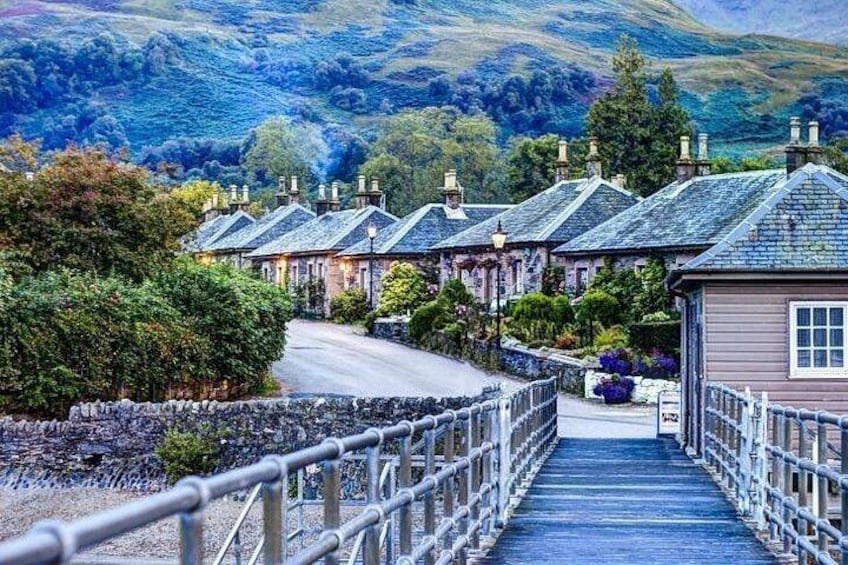Un puente de piedra que conduce a una hilera de casas tradicionales con tejados de paja. 2