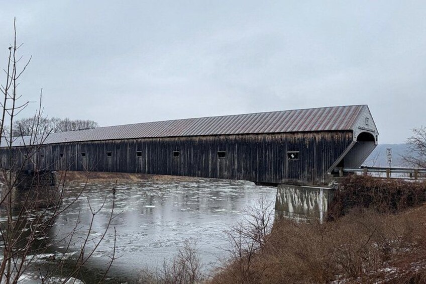 A wooden covered bridge over a frozen river. 2