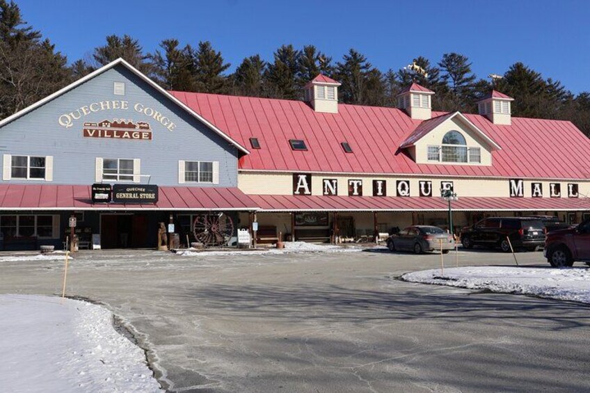A building with a red roof and a sign that reads "Antique Mall." 1