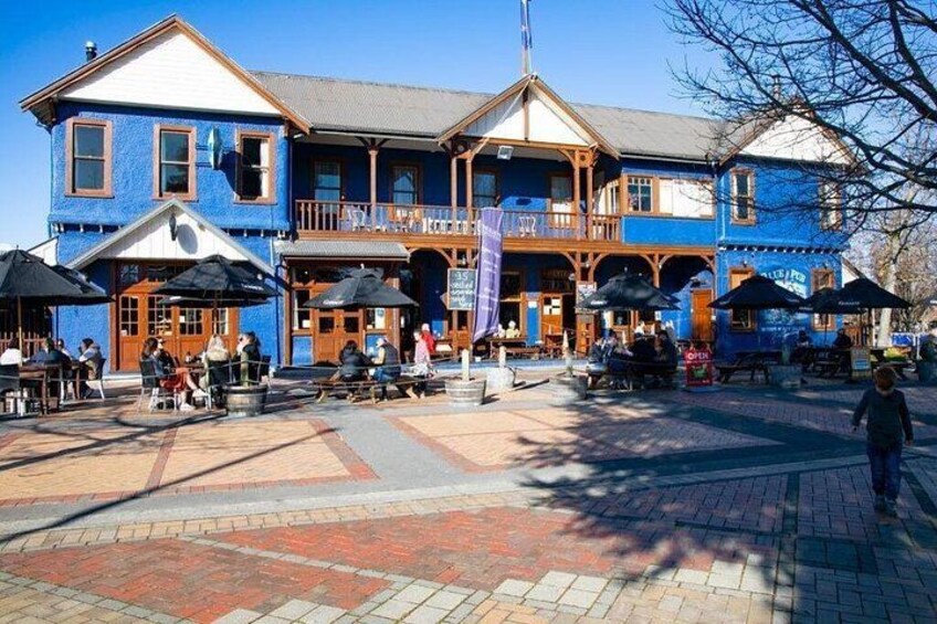 A blue building with outdoor seating and a flagpole. 4