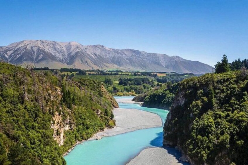 A turquoise river winding through a mountainous landscape with dense forests and rocky cliffs. 2