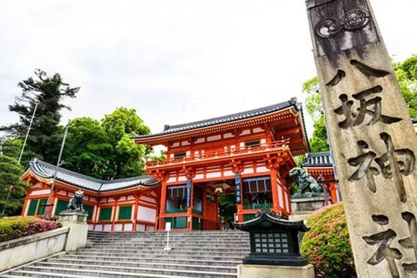 A traditional Japanese temple with a red torii gate, stone lanterns, and a stone monument with Japanese characters. 4