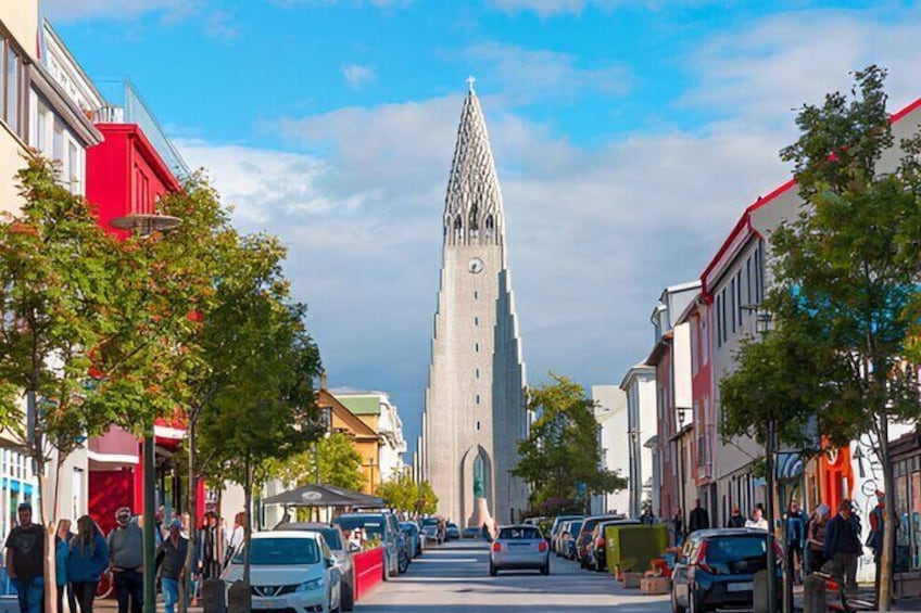 A street leading to a tall, pointed building with a clock. 3