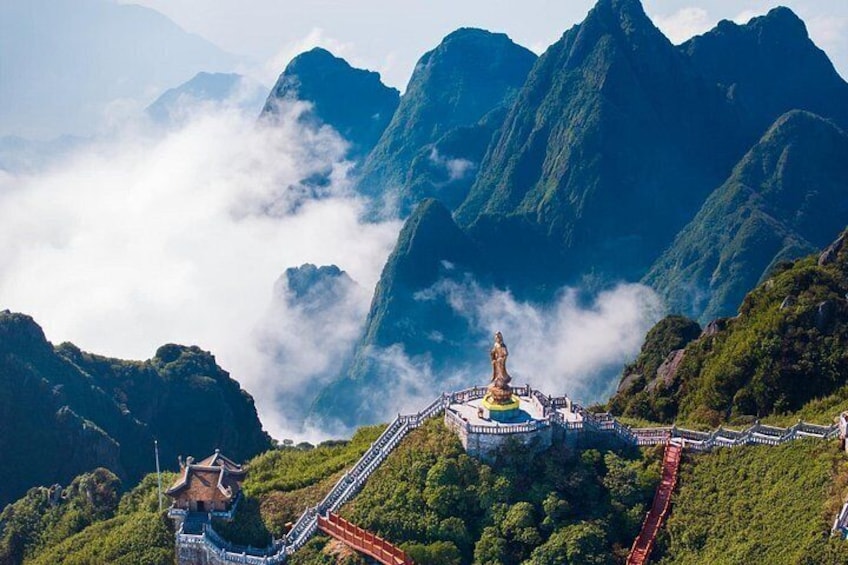 A mountainous landscape with a temple complex, a statue, and a red staircase. 4