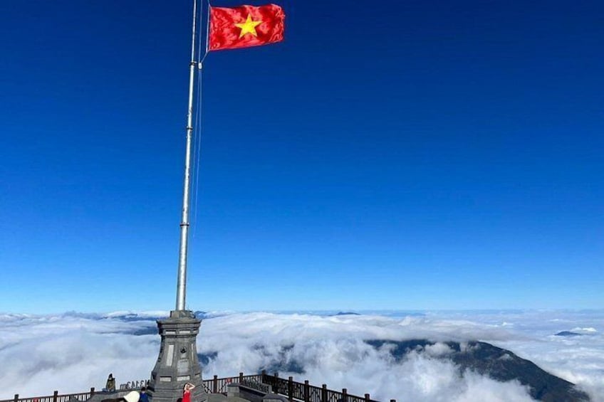 A flagpole with a flag, a mountain peak, and a cloud-covered landscape. 3