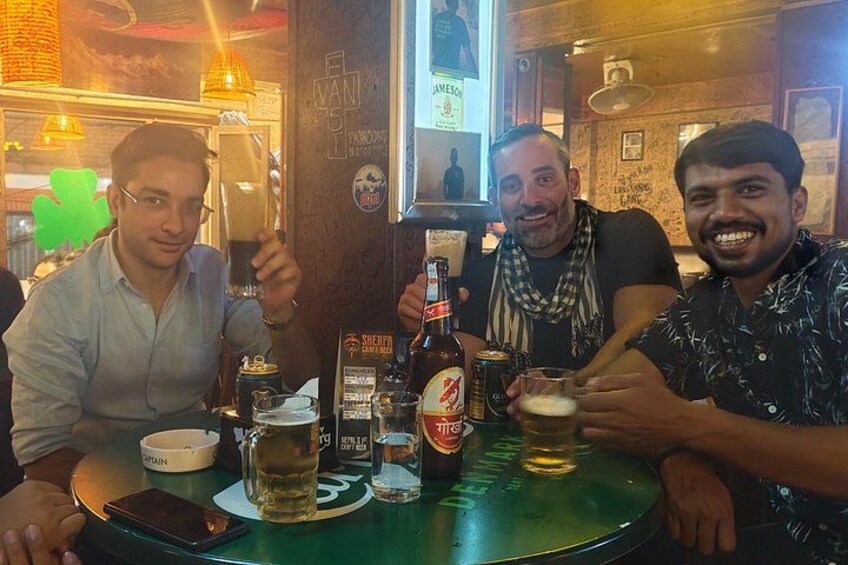 Trois personnes sont assises à une table, devant des boissons et un téléphone intelligent. 2