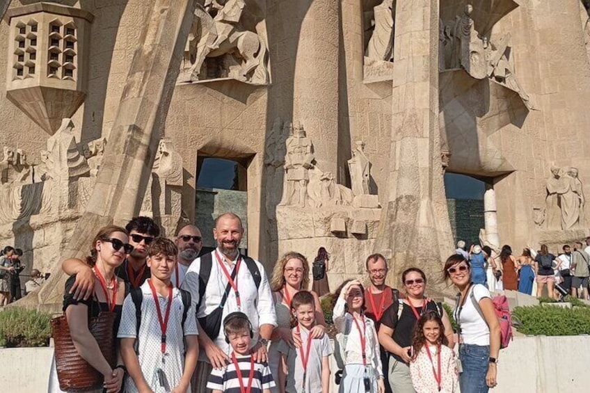 A group of people posing in front of a large, intricately carved stone structure with multiple statues and reliefs. 1
