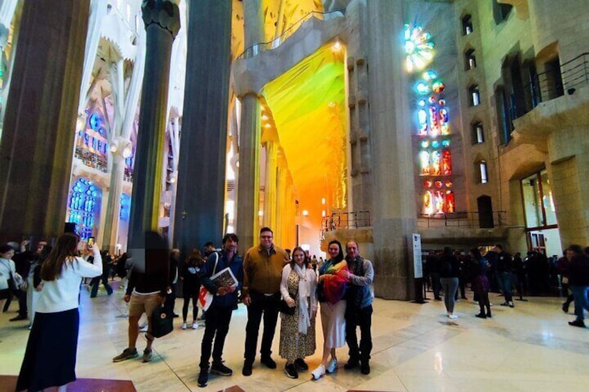A group of people inside a large, ornately decorated building with high ceilings and stained glass windows. 4