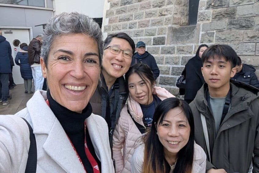 A group of people standing in front of a stone building. 3