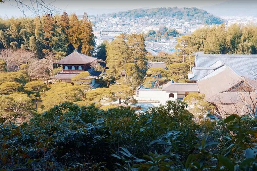 Un templo japonés tradicional rodeado de exuberante vegetación y un paisaje urbano al fondo. 2