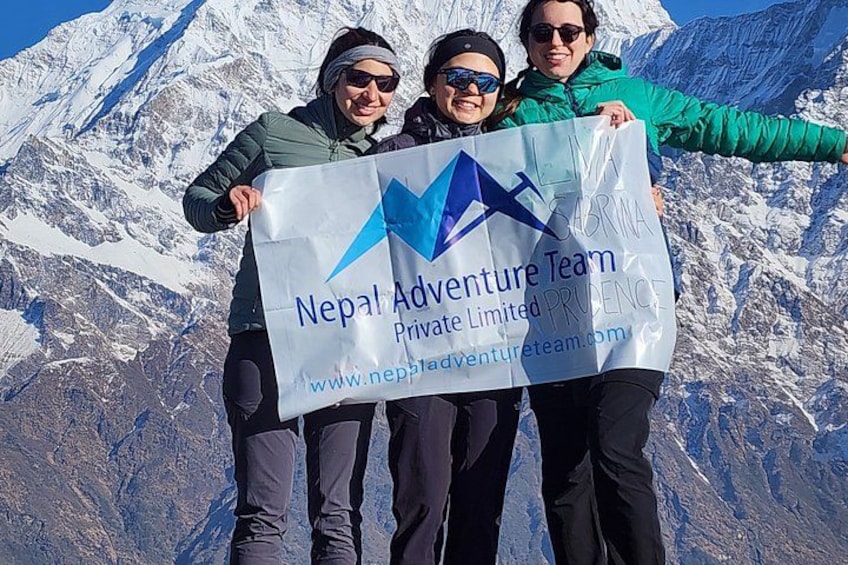 Trois personnes tenant une bannière ornée du logo et de l’adresse du site web de Nepal Adventure Team. 5
