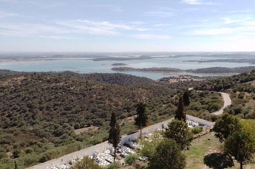 Un paisaje costero con vegetación densa, un camino sinuoso y una gran masa de agua a lo lejos. 3