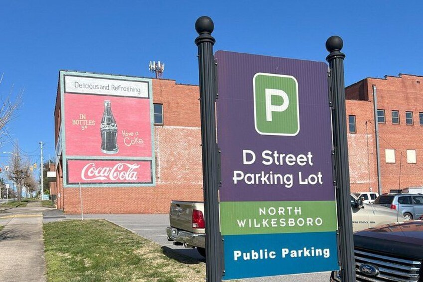 Señal de estacionamiento para el estacionamiento D Street en North Wilkesboro, con un anuncio de Coca-Cola al fondo. 4