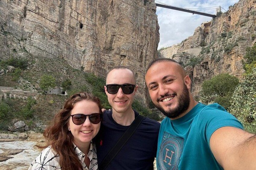 Tre personer som tar en selfie med en bergig kanjon och en bro i bakgrunden. 3