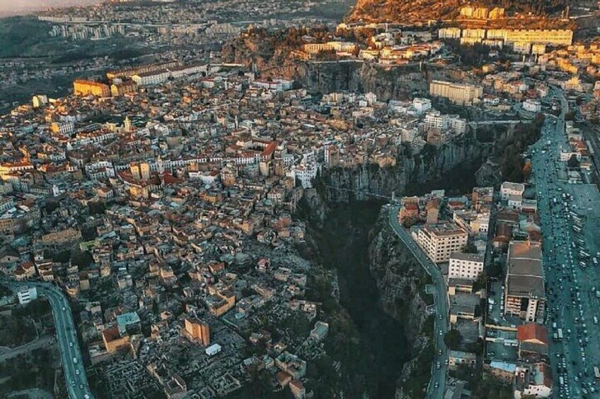 Vista aérea de una ciudad con un castillo destacado en una colina, zona urbana densa y un río. 1