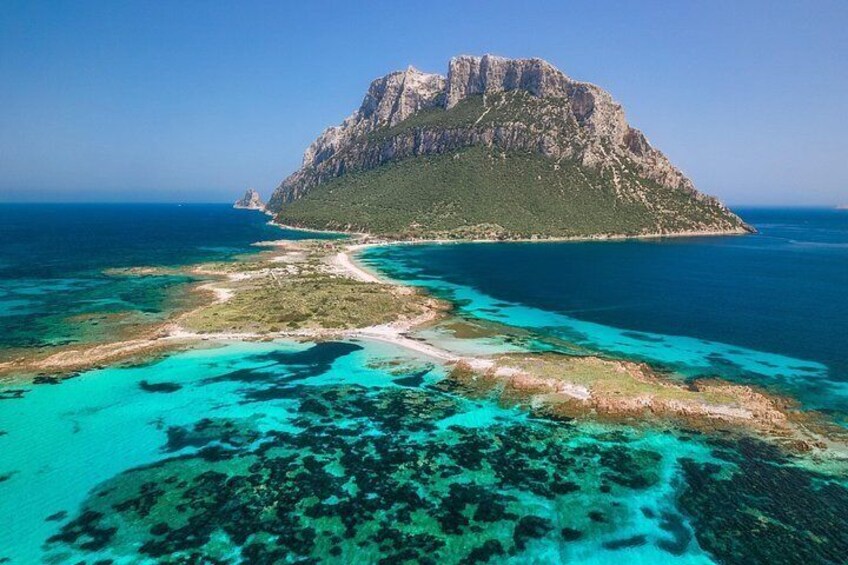 A mountainous island with clear turquoise waters and a visible coastline. 1