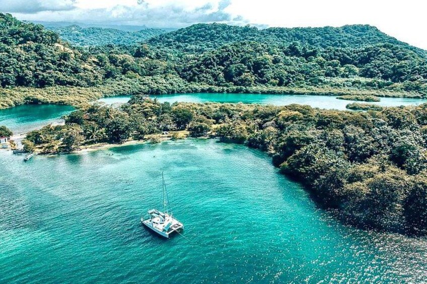 Een boot op turquoise water, omringd door weelderige groene heuvels. 1