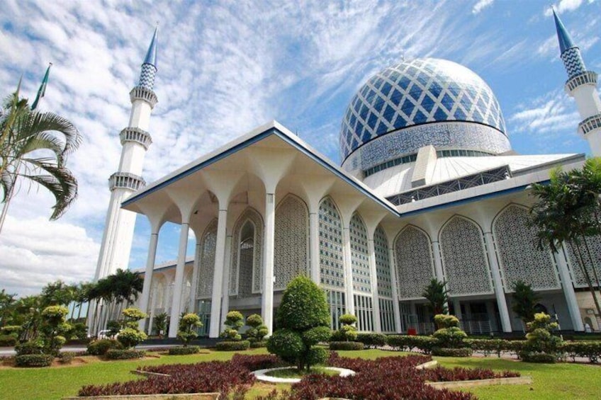 Une mosquée dotée d’un grand dôme et de minarets, entourée de jardins bien entretenus et de palmiers. 3