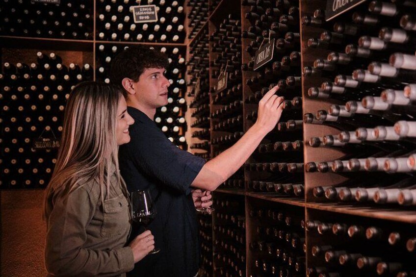 A person selecting a bottle from a wine rack in a cellar. 2