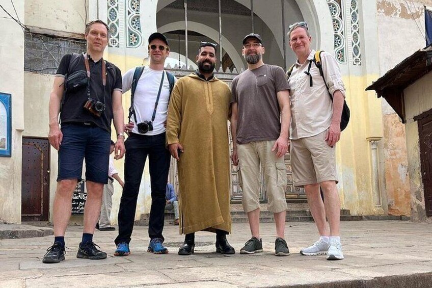 Five people standing in front of a building with a large arched doorway. 1