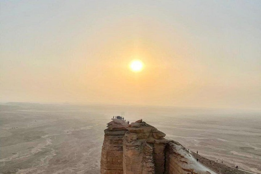A desert landscape with a rock formation and a distant sun. 1