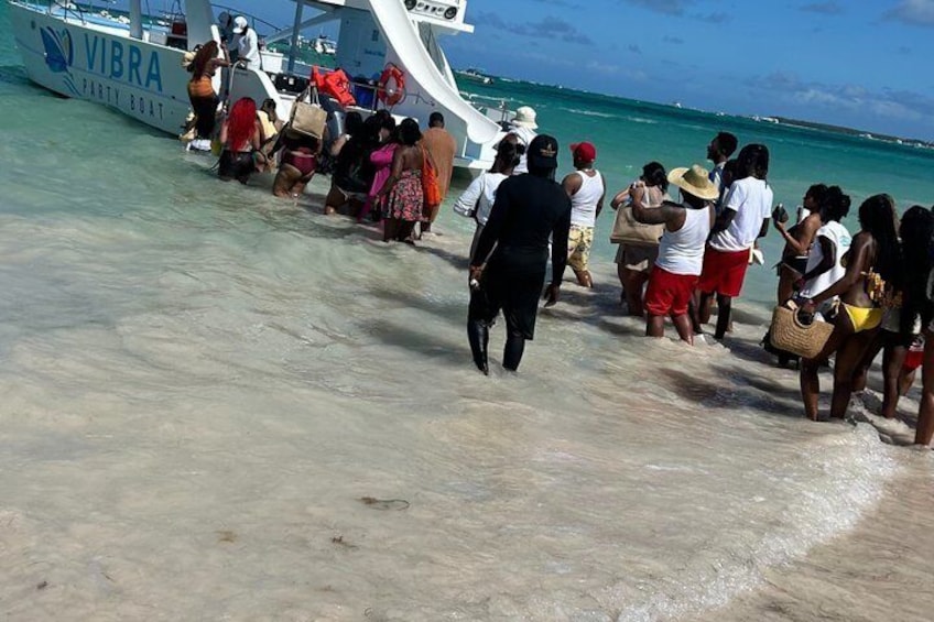 Un grupo de personas desembarca de un bote llamado 'VIBRA' en una playa de arena. 5